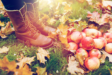 Image showing woman feet in boots with apples and autumn leaves