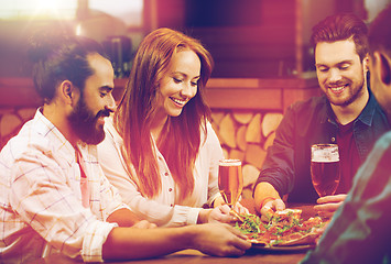 Image showing friends sharing pizza with beer at pizzeria