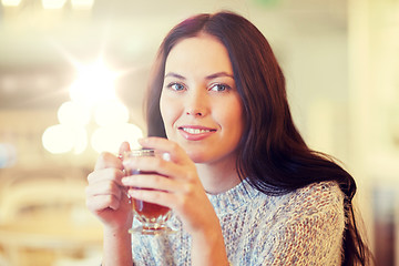 Image showing smiling young woman drinking tea at cafe