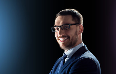 Image showing smiling businessman in glasses over black