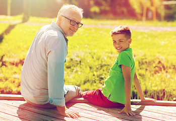 Image showing grandfather and grandson sitting on river berth