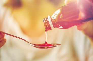 Image showing woman pouring medication from bottle to spoon