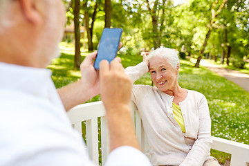 Image showing old man photographing woman by smartphone in park