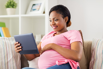 Image showing happy pregnant woman with tablet pc at home