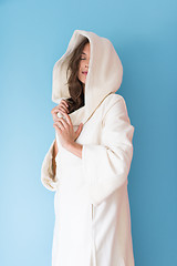 Image showing woman in a white coat with hood isolated on blue background