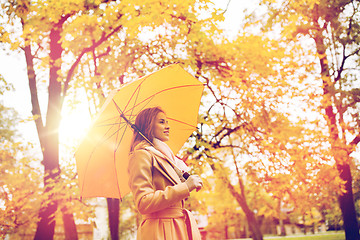 Image showing happy woman with umbrella walking in autumn park