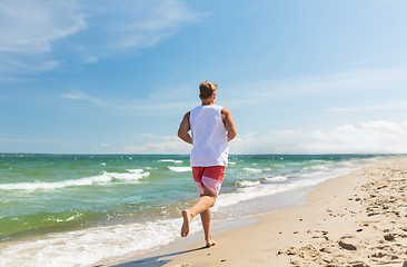 Image showing happy man running along summer beach