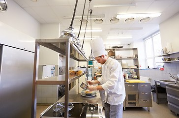 Image showing happy male chef cooking food at restaurant kitchen