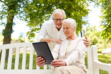 Image showing happy senior couple with tablet pc in city park