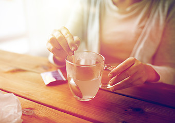 Image showing woman stirring medication in cup with spoon