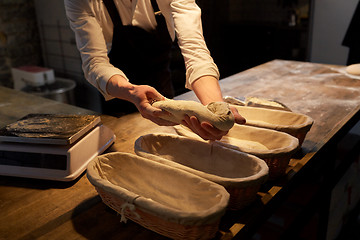 Image showing baker with dough rising in baskets at bakery