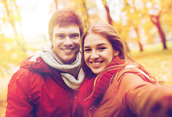 Image showing happy young couple taking selfie in autumn park