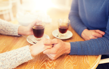 Image showing close up of couple holding hands at restaurant