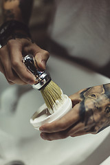 Image showing Crop tattooed barber making foam