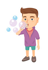 Image showing Little caucasian boy blowing soap bubbles.