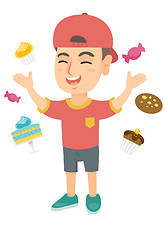 Image showing Happy caucasian boy standing among lots of sweets.