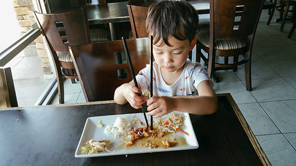 Image showing Cute Young Chinese and Caucasian Boy Learning To Use Chopsticks 