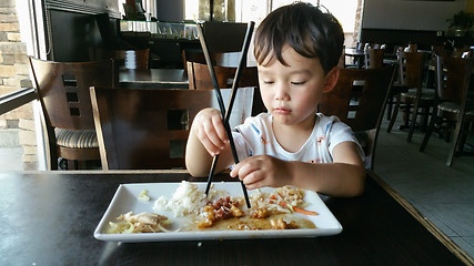 Image showing Cute Young Chinese and Caucasian Boy Learning To Use Chopsticks 