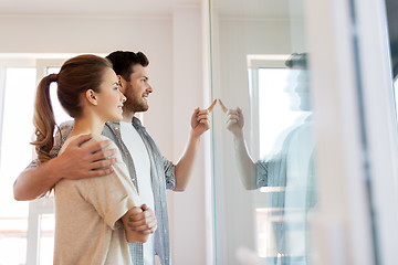 Image showing happy couple looking through window at new home