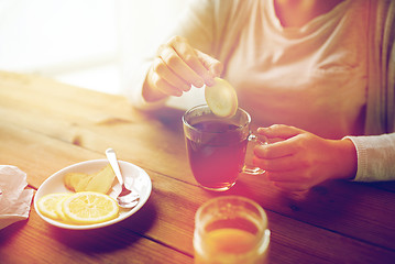 Image showing close up of woman adding lemon to tea cup