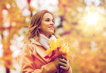 Image showing beautiful woman with maple leaves in autumn park