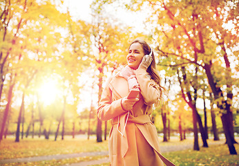 Image showing woman with smartphone and earphones in autumn park