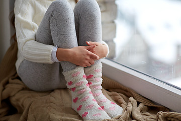 Image showing girl sitting on sill at home window in winter