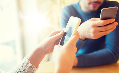 Image showing close up of couple with smartphones at cafe