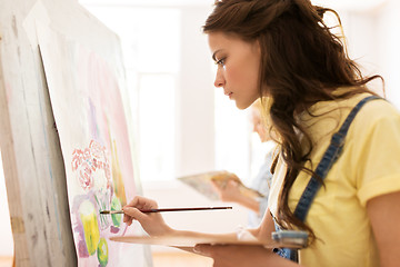 Image showing student girl with easel painting at art school