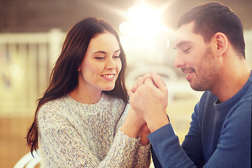 Image showing happy couple holding hands at restaurant or cafe