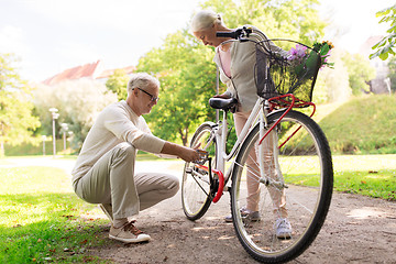 Image showing happy senior couple with bicycle at summer park