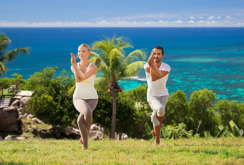 Image showing smiling couple making yoga exercises outdoors