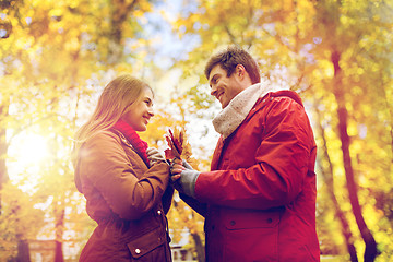 Image showing happy couple with maple leaves in autumn park