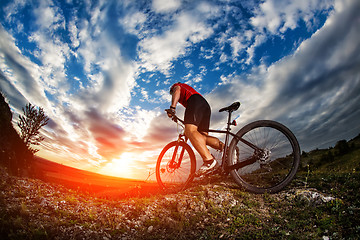 Image showing cyclist riding mountain bike on rocky trail at sunrise