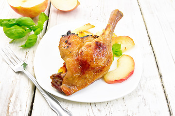 Image showing Duck leg with apple in plate on board