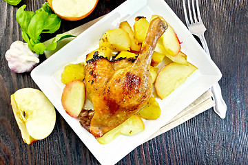 Image showing Duck leg with apple and basil in plate on board top