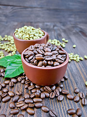 Image showing Coffee black and green grains in cups with leaf on board