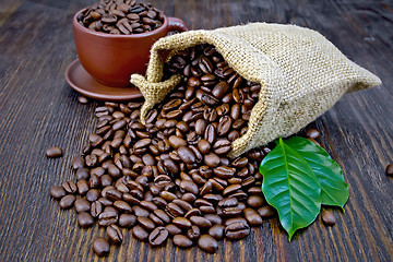 Image showing Coffee black grains in bag with cup and leaf on board