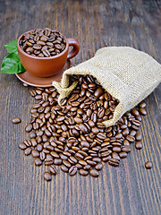 Image showing Coffee black grains in bag with cup on dark board