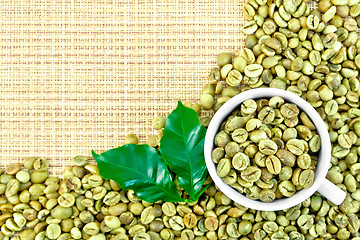 Image showing Coffee green grains with cup on yellow woven fabric