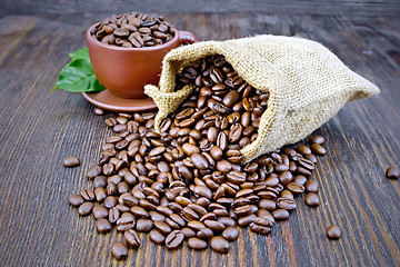 Image showing Coffee black grains in bag with cup on board