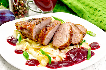 Image showing Duck breast with plum sauce and cabbage in plate on board