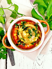 Image showing Fish baked with tomato in red pot on napkin top