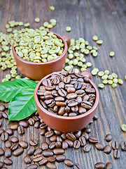 Image showing Coffee black and green grains in cups with leaf on dark board