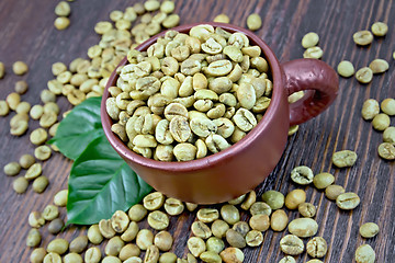 Image showing Coffee green grain in cup with leaf on board
