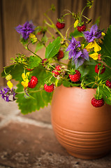 Image showing Ripe strawberries and a bouquet of forest flowers in a clay mug