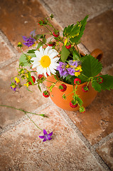 Image showing Ripe strawberries and a bouquet of forest flowers in a clay mug