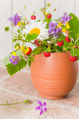 Image showing Ripe strawberries and a bouquet of forest flowers in a clay mug