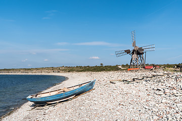 Image showing Blue rowing boat and an old windmill by seaside