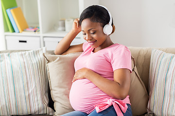 Image showing pregnant woman in headphones at home